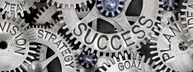 Macro photo of tooth wheel mechanism with SUCCESS concept letters